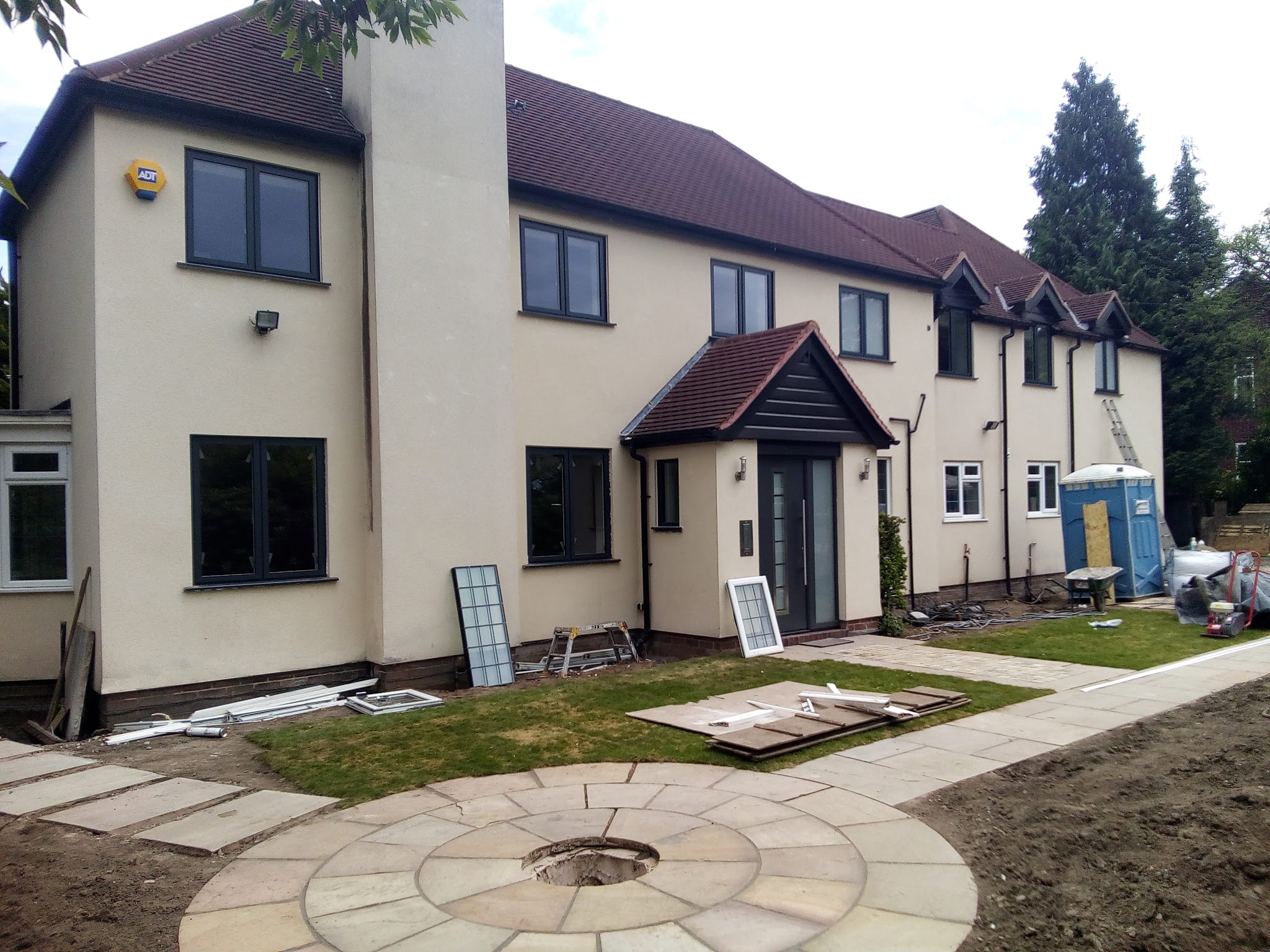 The rear of a large rendered house with new dark-framed windows