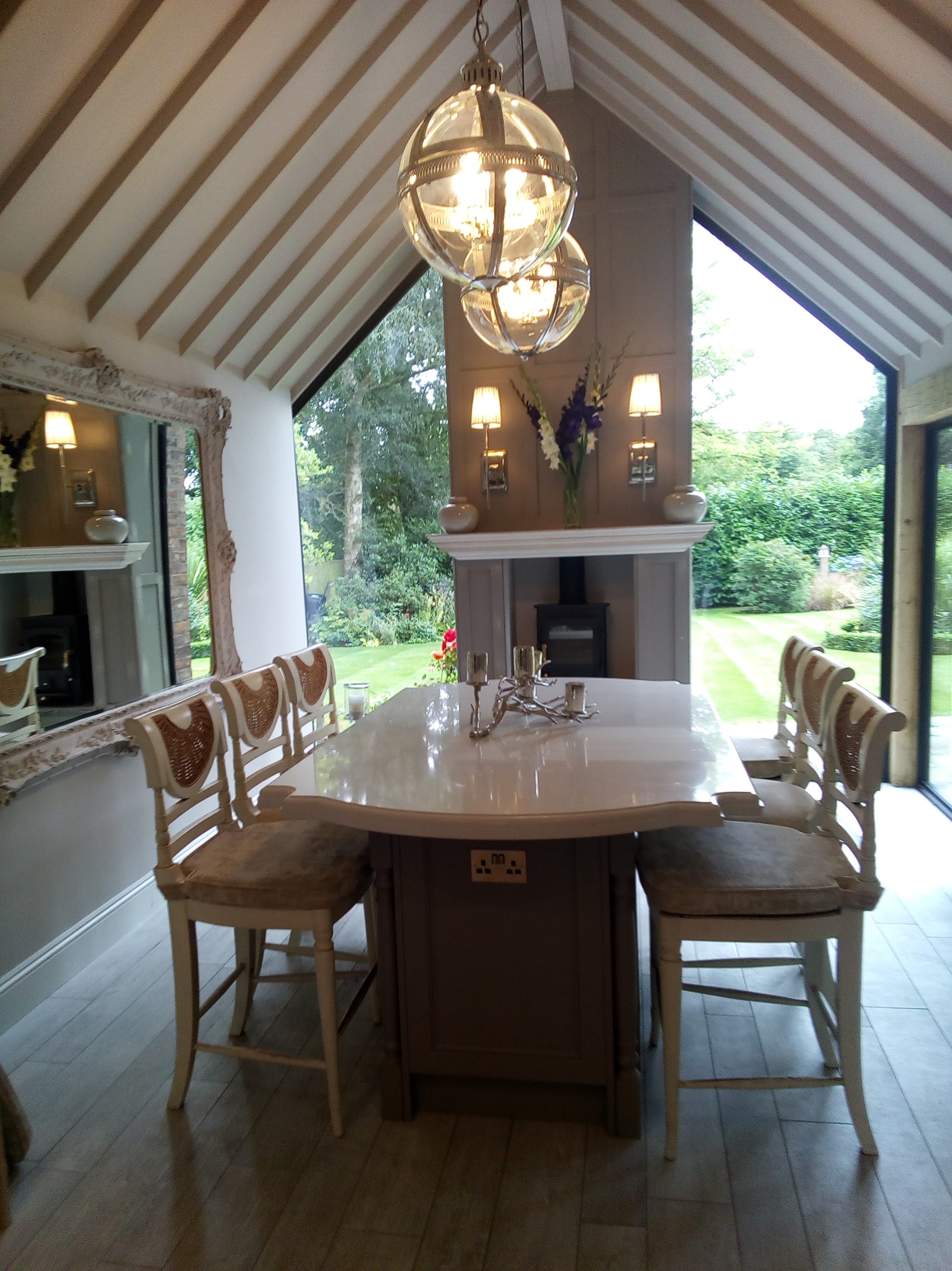 The inside of a glazed gable end over a dining table, looking out onto a garden