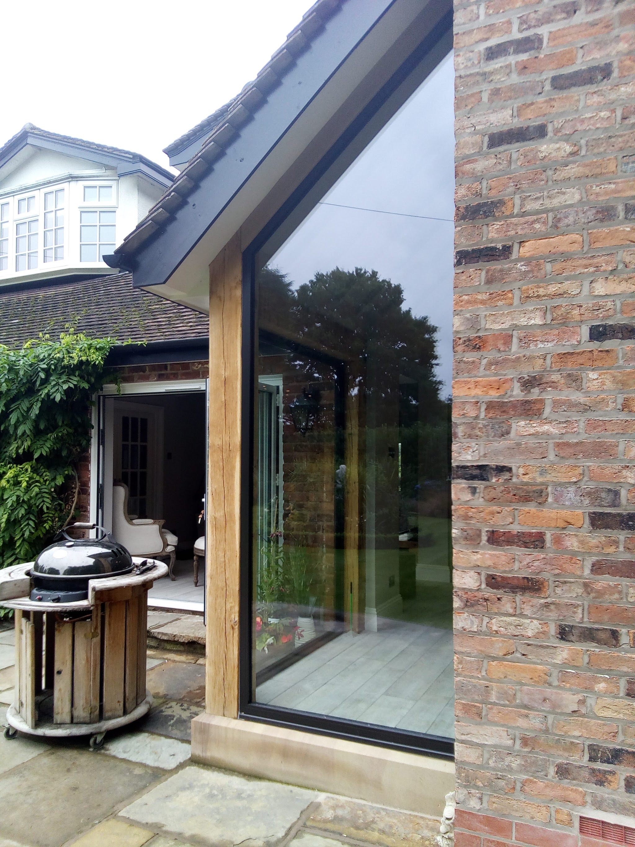 A corner of floor-to-ceiling glazing meeting an oak post and brickwork