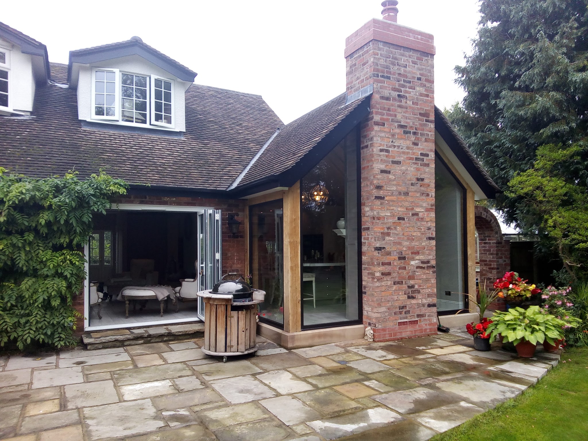 A brick and glass extension with a chimney opening onto a flagged patio